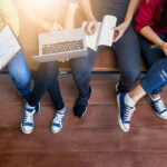 Vier studierende sitzen auf einer Bank mit Laptop