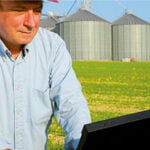 Landwirt auf Feld mit Laptop