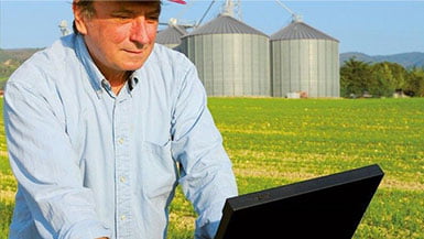 Landwirt auf Feld mit Laptop