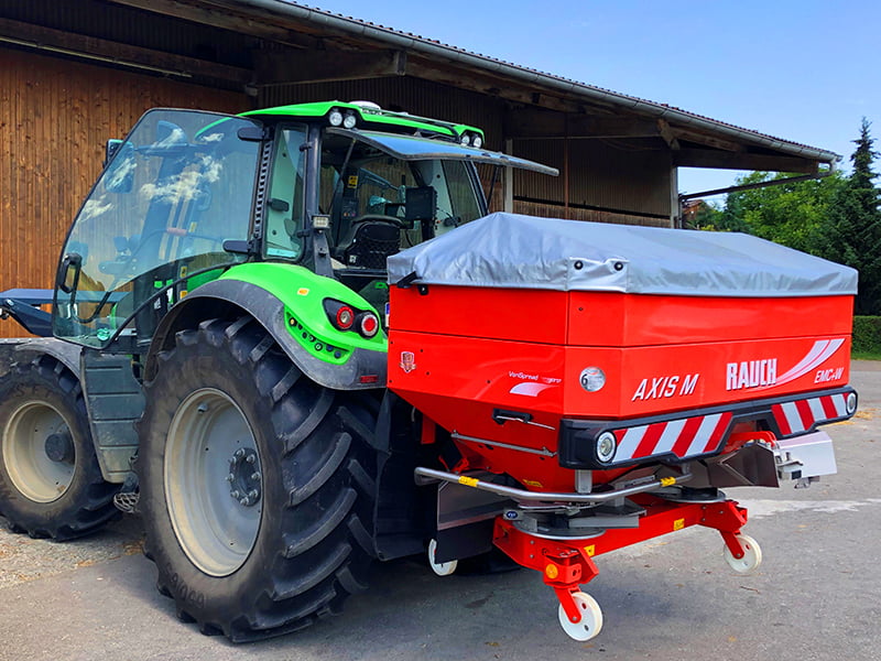 Ein Deutz Traktor mit einem Düngerstreuer von hinten.