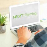 Laptop NEXT Farming felirattal egy asztalon