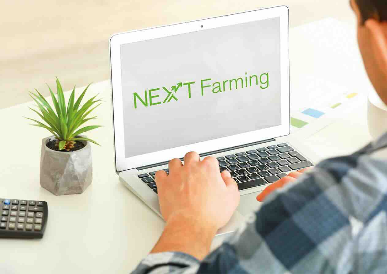 Laptop NEXT Farming felirattal egy asztalon